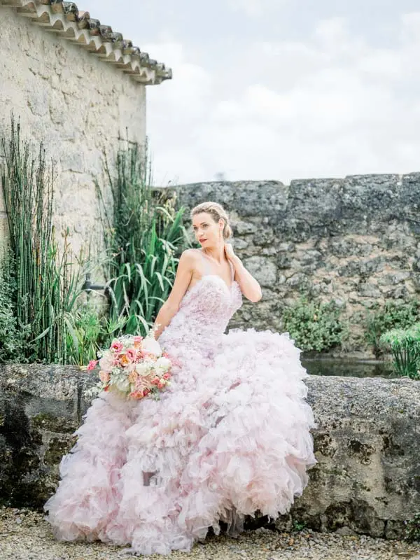 Bride in a pink tulle gown on the stone walls of Château Soutard, Saint-Émilion
